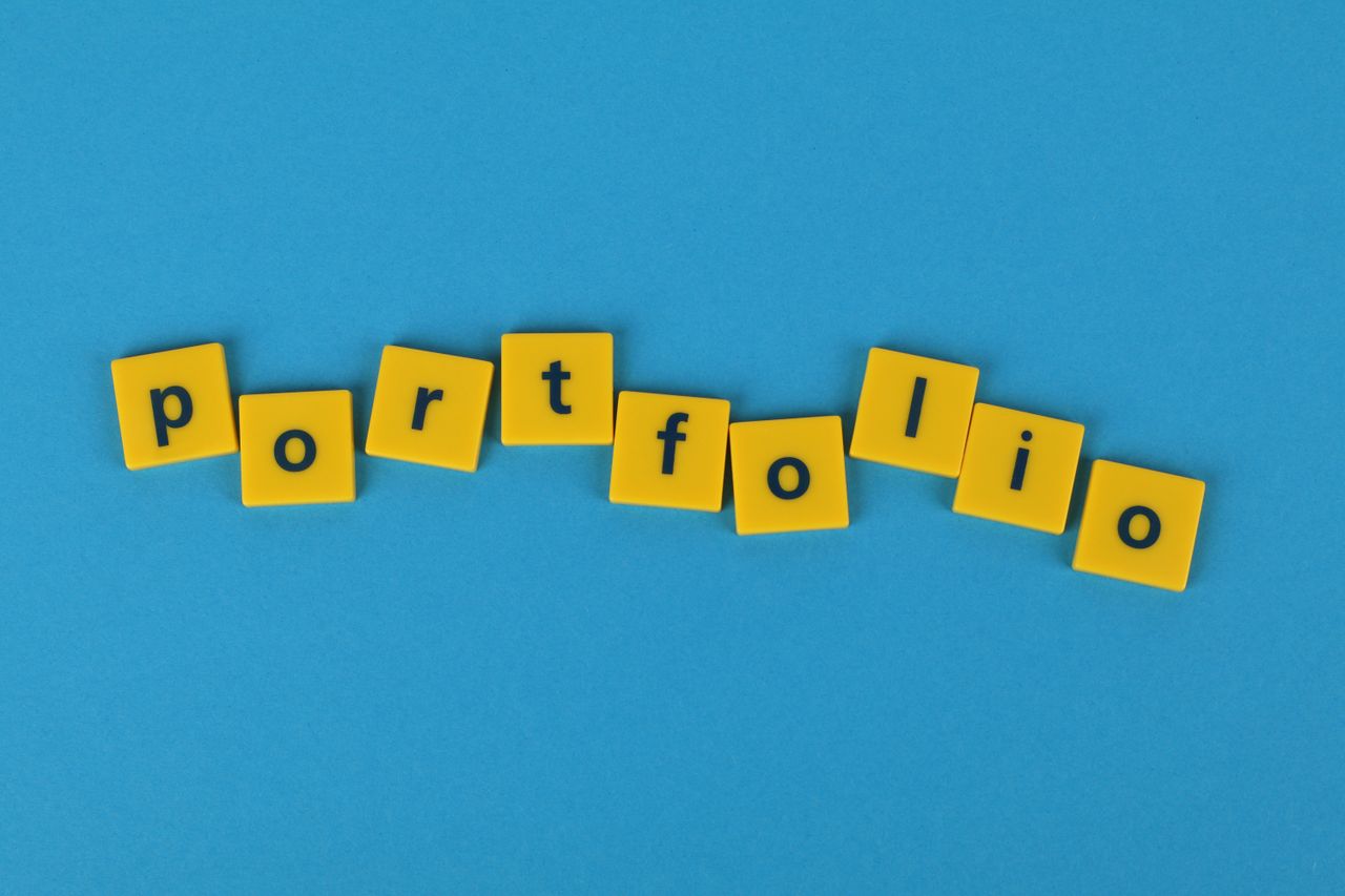 heros-img Yellow Scrabble tiles on a blue background spelling portfolio. Perfect for business themes.